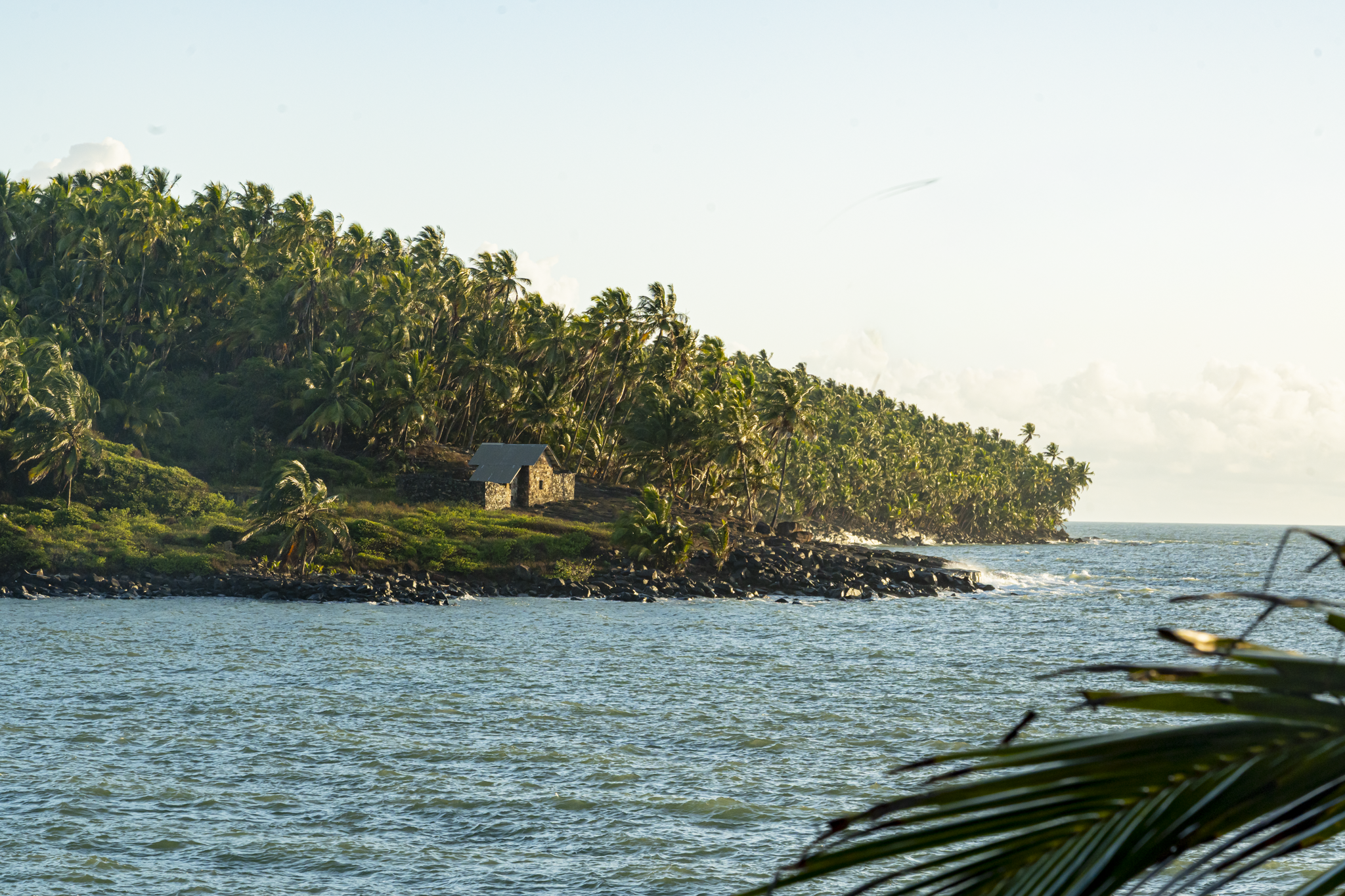 Bâtiment de l’Hostellerie des Îles, pierre de latérite et coursives, au milieu des arbres de l’Île Royale